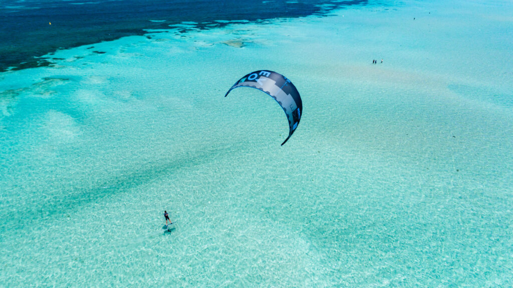 A kitesurfer foils over shallow, turqoise waters off the coast of Western Australia