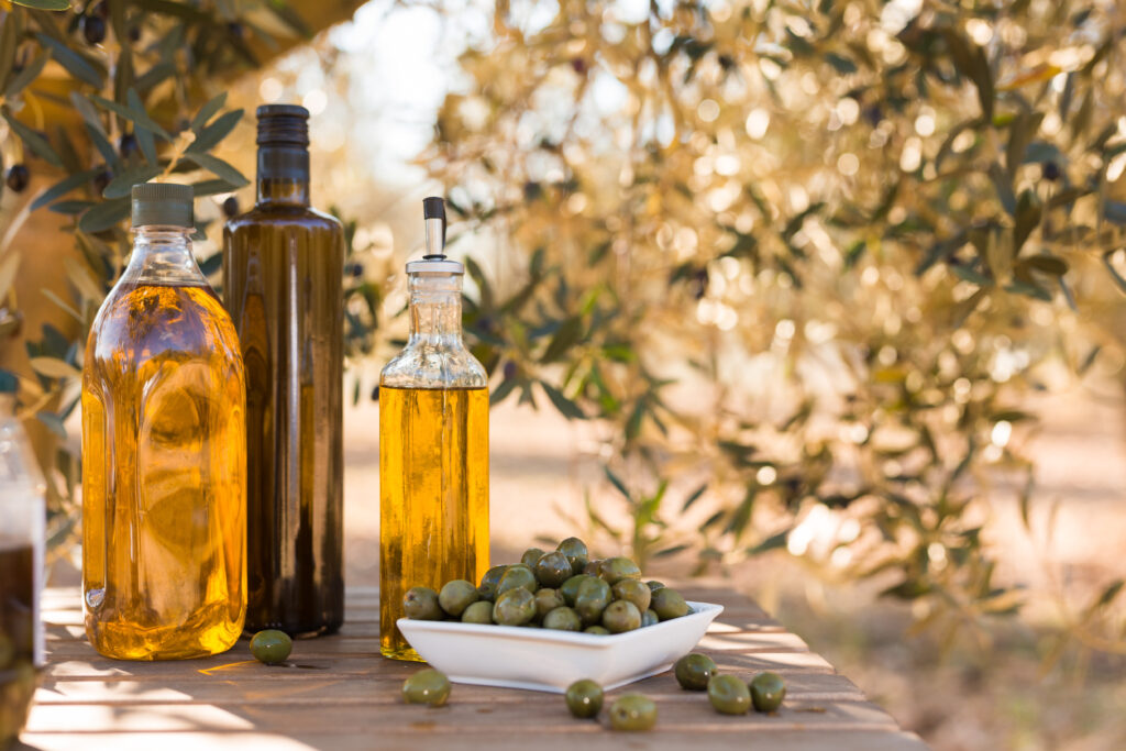 still life with green olives and oil on table in olive grove